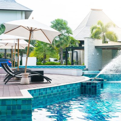 Beautiful luxury hotel swimming pool resort with umbrella and chair - with sunflare effect